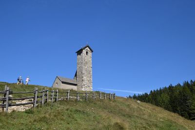 Lighthouse on field against clear blue sky