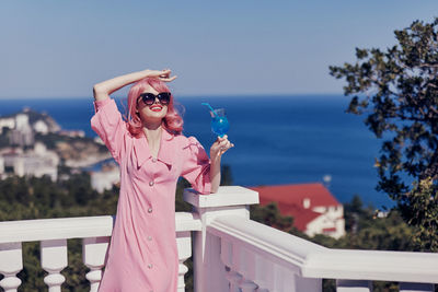 Portrait of young woman wearing sunglasses while standing against sky