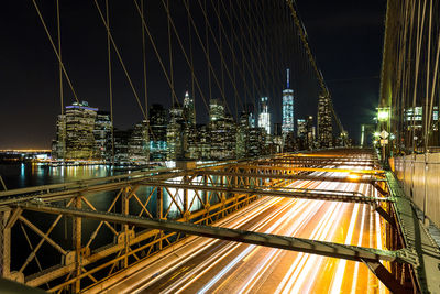 Illuminated bridge and buildings against sky at night
