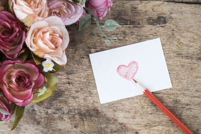 Heart shape on envelope by flowers at table
