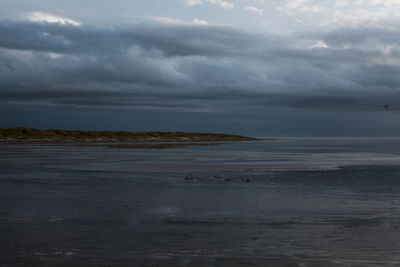 Scenic view of calm sea against cloudy sky