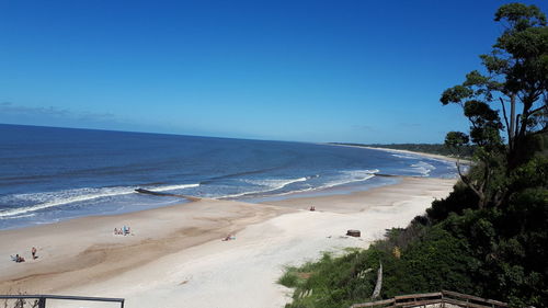 Scenic view of beach against clear blue sky