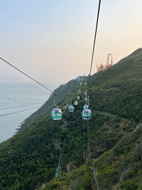 Cable car hanging by sea against sky