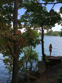 Rear view of woman standing by tree against sky