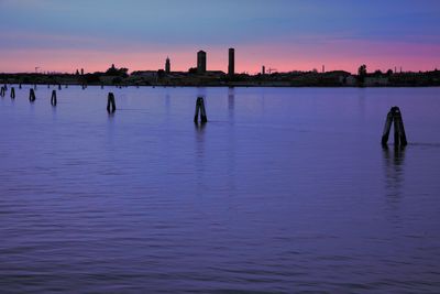 Silhouette people in lake against sky during sunset