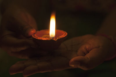 Close-up of hand holding lit candle