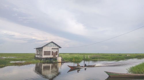 People sitting in boat on lake against sky