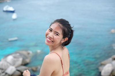 Portrait of young woman looking away against sea