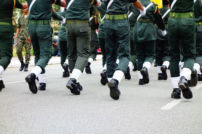 Low section of people wearing uniforms walking on street