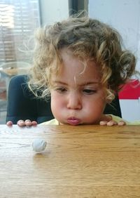 Close-up of little girl blowing crumpled paper ball on table