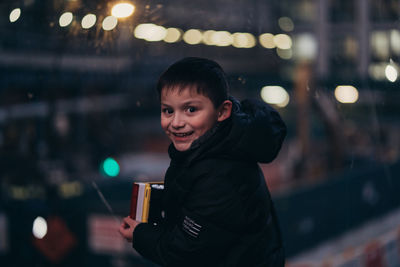 Portrait of smiling man holding drink at night
