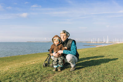 Grandfather and granddaughter at beach against sky