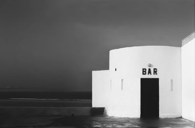 Information sign on building by sea against sky