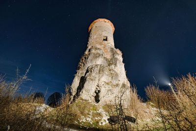 Low angle view of rock formation and tower against sky at night