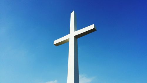 Low angle view of cross sign against blue sky