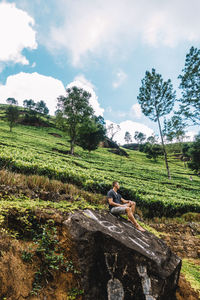 Woman sitting on field against sky