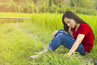 Side view of a young woman sitting on grass