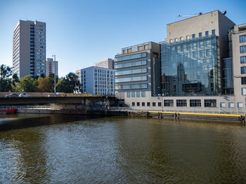 Buildings by river against clear sky