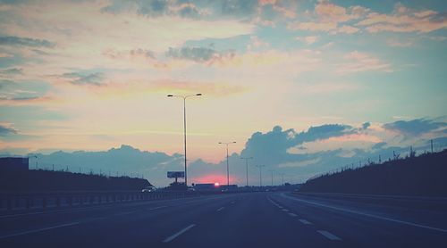 Cars on road against cloudy sky