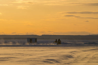 Motocrosso on frozen lake against sky during sunset