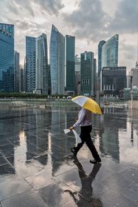Man standing by modern cityscape against sky