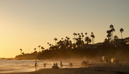 Group of people on beach against clear sky