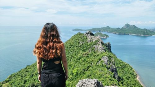 Rear view of woman standing by sea against sky