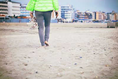 Low section of woman walking on sand at beach
