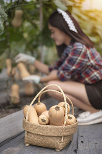 Midsection of woman sitting by wicker basket