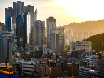 Modern buildings in city against sky during sunset