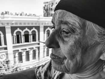 Close-up of senior woman looking away against buildings