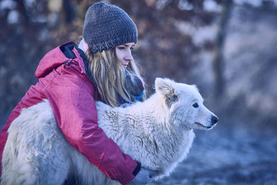 Woman embracing dog during winter