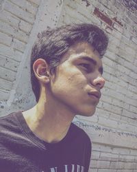 Portrait of young man looking away against wall