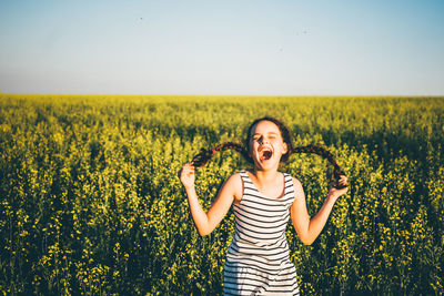 Portrait of young woman standing on field against clear sky