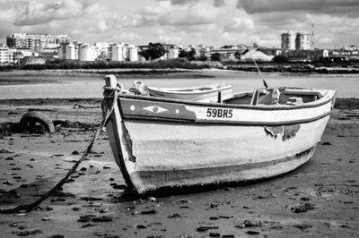 Old boat moored at beach by city