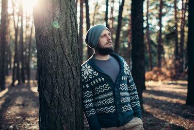 Thoughtful young man standing in forest