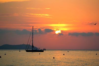 Sailboats in sea against sky during sunset