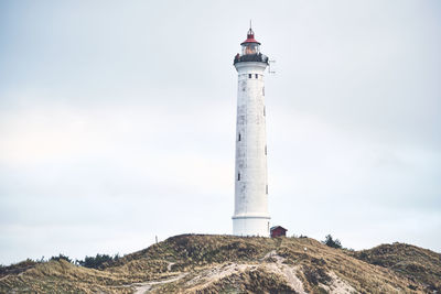 Lighthouse by sea against sky