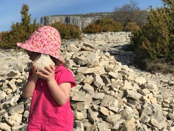 Close-up of girl holding rock while standing on field