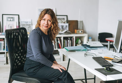 Charming adult woman middle aged woman with curly hair designer working on computer in modern office