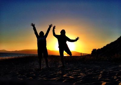 Silhouette of people on beach at sunset