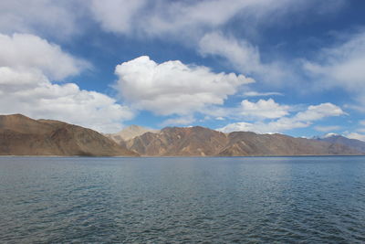 Scenic view of lake by mountains against cloudy sky