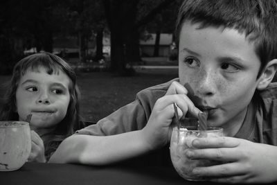 Cute siblings eating food while sitting outdoors