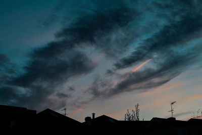 Low angle view of silhouette trees against dramatic sky