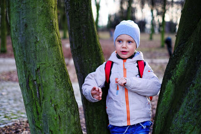 Boy standing amidst tree trunks at forest