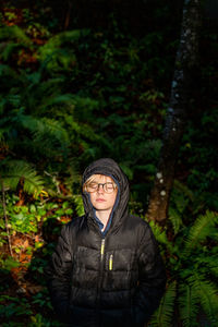 Portrait of mature man standing against trees in forest