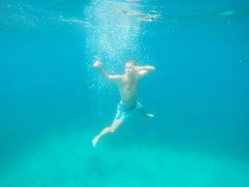 Shirtless man swimming in sea