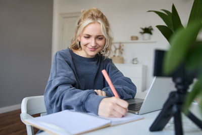 Portrait of smiling young woman writing in book