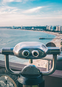 Close-up of coin-operated binoculars by sea against sky