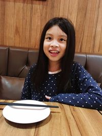 Portrait of smiling girl sitting on table